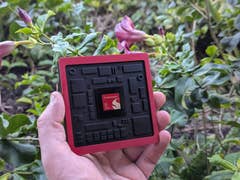 A person holding a Qualcomm Snapdragon 8 Elite Gen 5 chip surrounded by greenery.