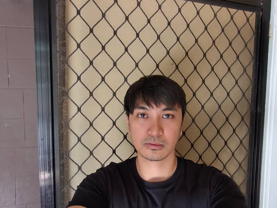 A person taking a selfie in front of a mesh security door.