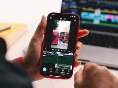 A person holding a smartphone displaying video editing software and a bus scene.