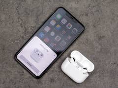 Apple AirPods Pro with charging case next to an iPhone on a table