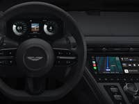 Interior view of a car showing the steering wheel and a digital display with navigation and media controls.