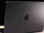 A black Apple MacBook Pro laptop viewed from the back on a light surface.