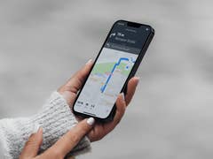 A person holding a smartphone displaying Apple Maps with a blue route towards Bernauer Straße.