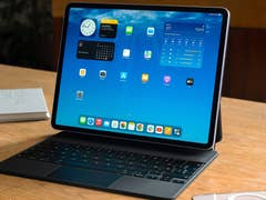 Apple iPad Air M3 on a wooden table with a keyboard and various app icons displayed on the screen.