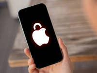 A hand holding an Apple iPhone 15 Pro displaying a locked Apple logo on the screen.