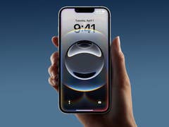 A person holding an Apple iPhone 16e displaying a circular abstract lock screen image.