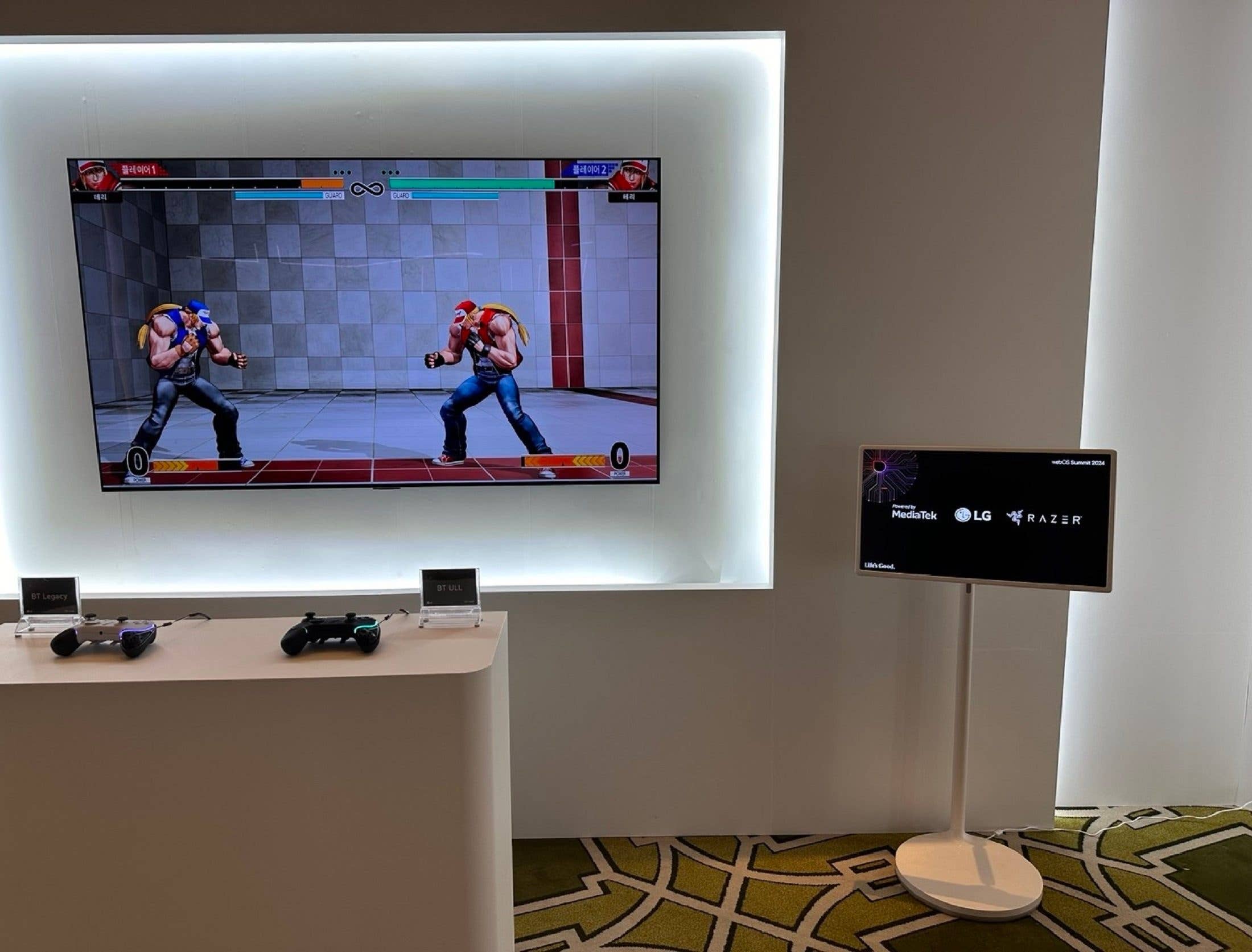 A gaming setup featuring a smart TV displaying a fighting game, with controllers visible in front. A gaming setup featuring a smart TV displaying a fighting game, with controllers visible in front.
