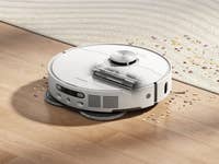 A Dreame L40 Ultra AE robot vacuum cleaning a wooden floor with debris around it.
