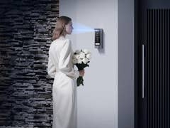 A woman in a white dress stands near the EZVIZ HP7 Pro device, holding a bouquet of flowers.
