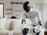 A humanoid robot interacting with a tablet in a modern living room.