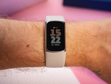 A person's wrist displaying a Fitbit Charge 6 with the date 21 NOV and time 15:22.