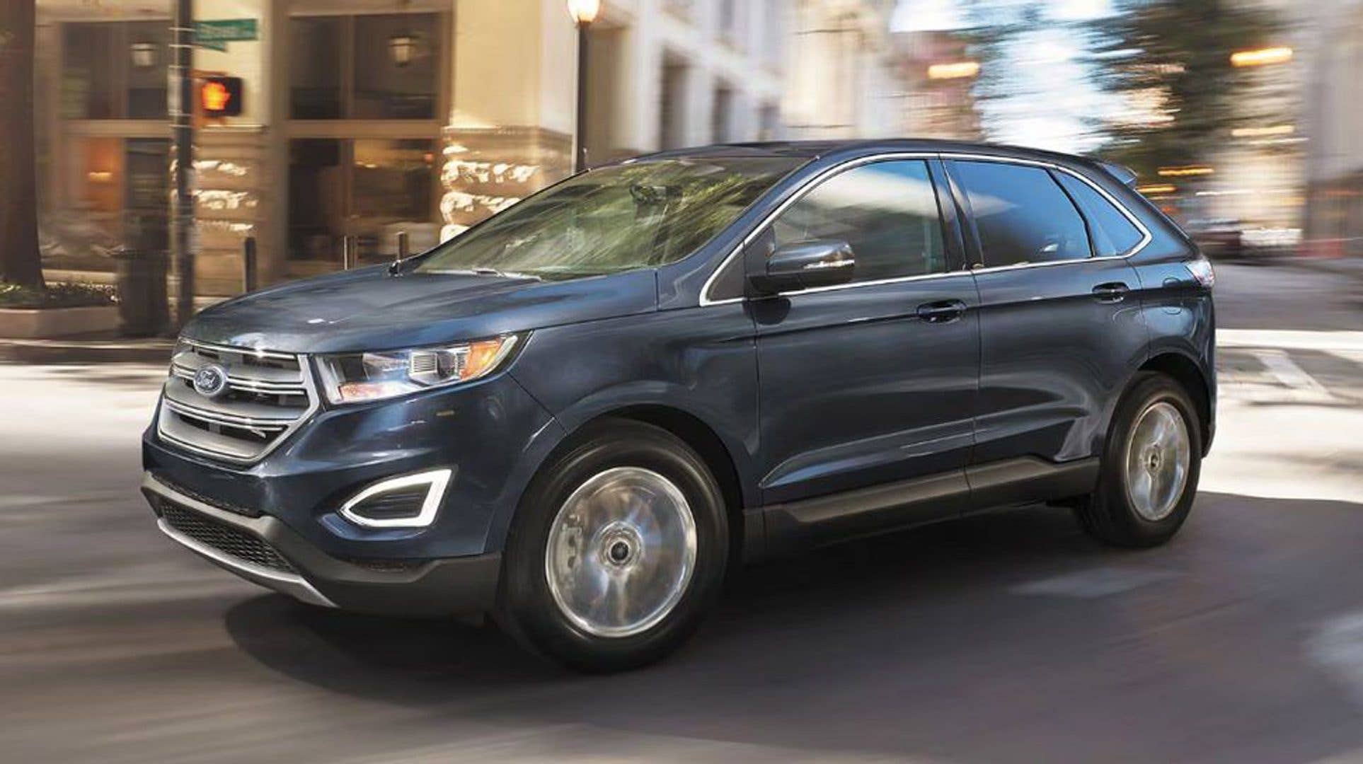 A blue Ford SUV driving through a city street.