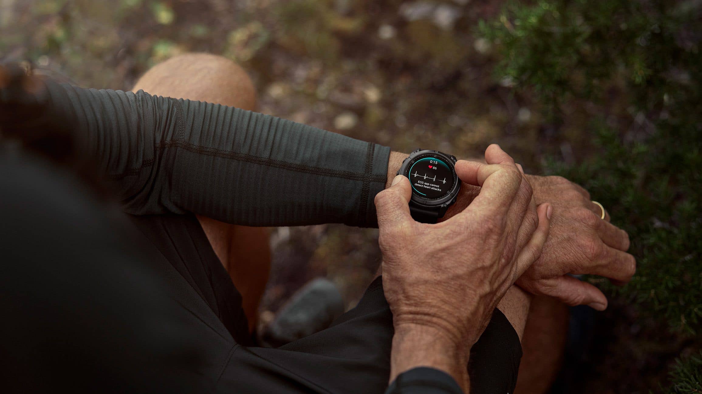 A person checking a Garmin smartwatch on their wrist in an outdoor setting.