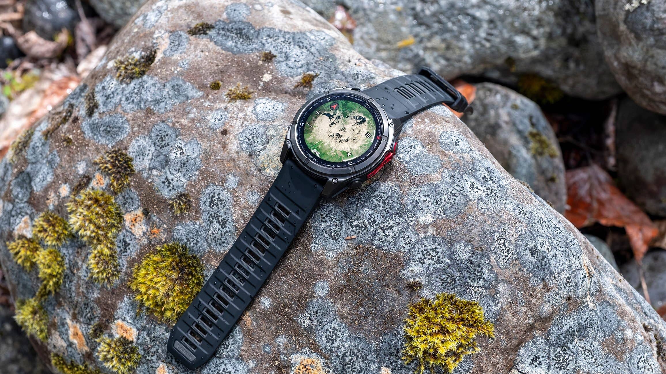 A Garmin watch displayed on a mossy rock in a natural setting.