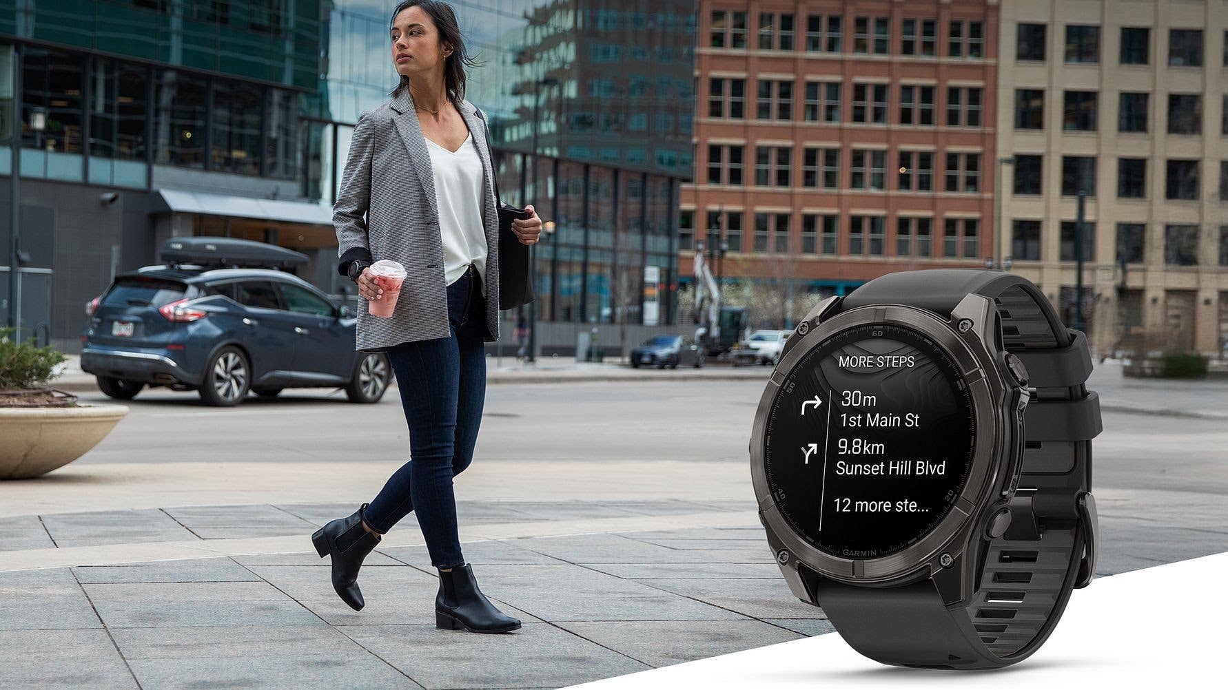 A woman walking in a city wearing a blazer, holding a drink, with a Garmin watch displaying directions.