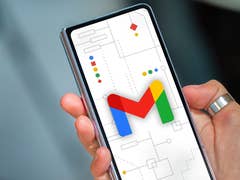 A hand holding a smartphone displaying the Gmail logo on a background with geometric shapes.