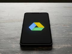 A smartphone displaying the Google Drive logo on a wooden surface.