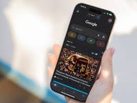 A hand holding a smartphone displaying Google News with a headline about the Philippines' Black Nazarene procession.