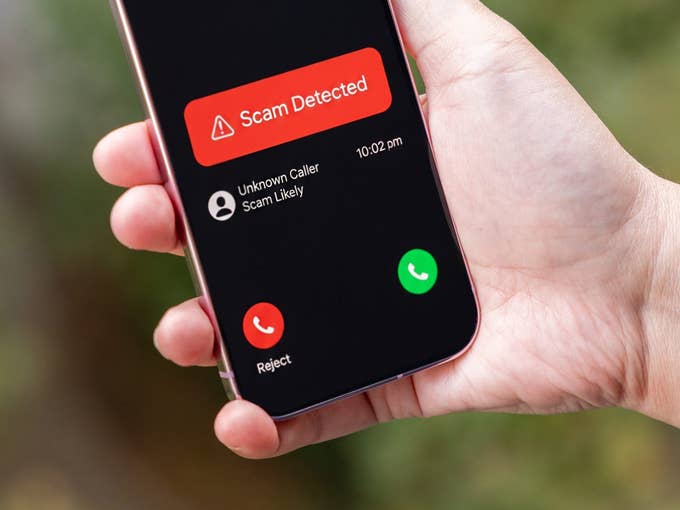 A hand holding a Google Pixel 9 Pro displaying a scam call alert.
