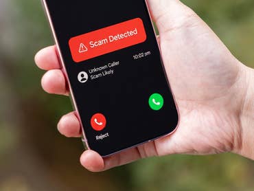 A hand holding a Google Pixel 9 Pro displaying a scam call alert.