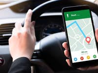 Woman sitting in front of the driver in the car I'm using a smartphone to look at a map showing the route of travel. And use the application to get to the destination. Black car steering wheel handle.