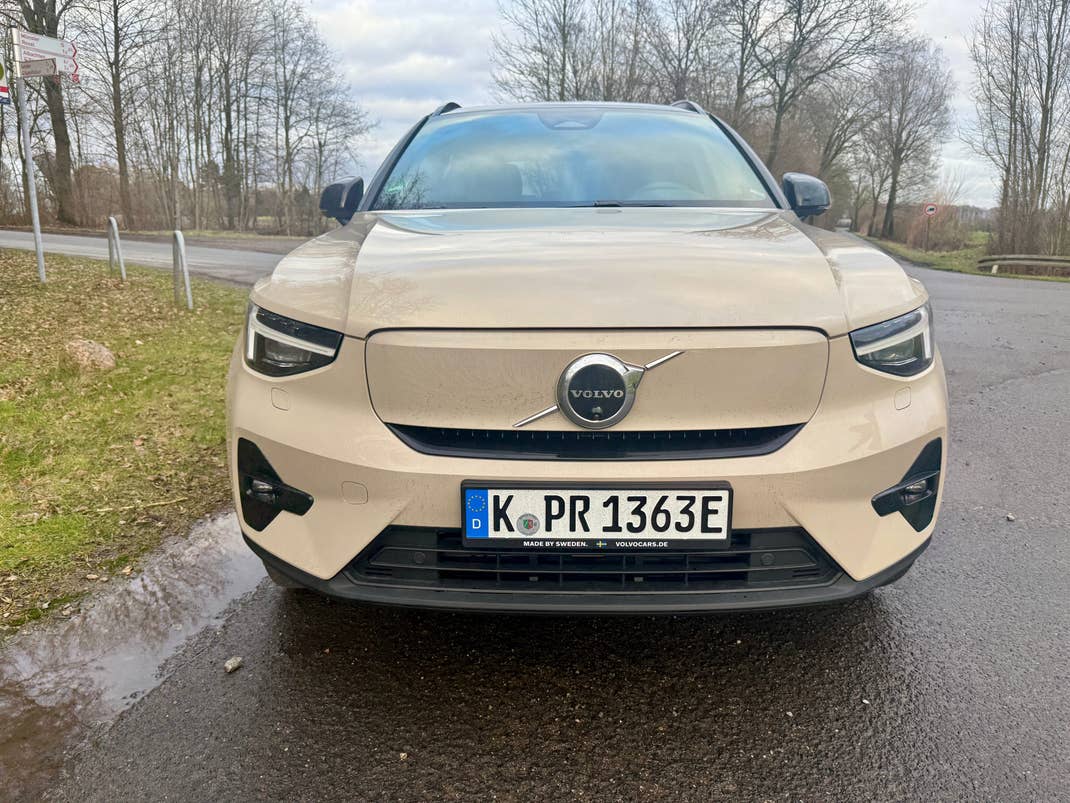 Front view of a beige Volvo EX40 SUV parked on a road.