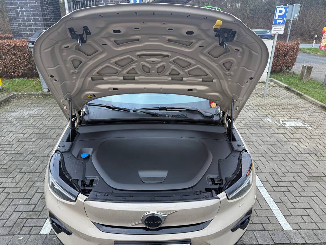Open hood of a Volvo EX40, revealing the engine compartment with a dark cover and a blue cap.