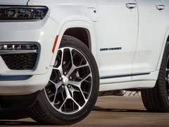 Close-up of a white Jeep Grand Cherokee L showing the front wheel and brand badge.