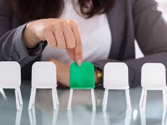 A person choosing a green seat in a row of white chairs