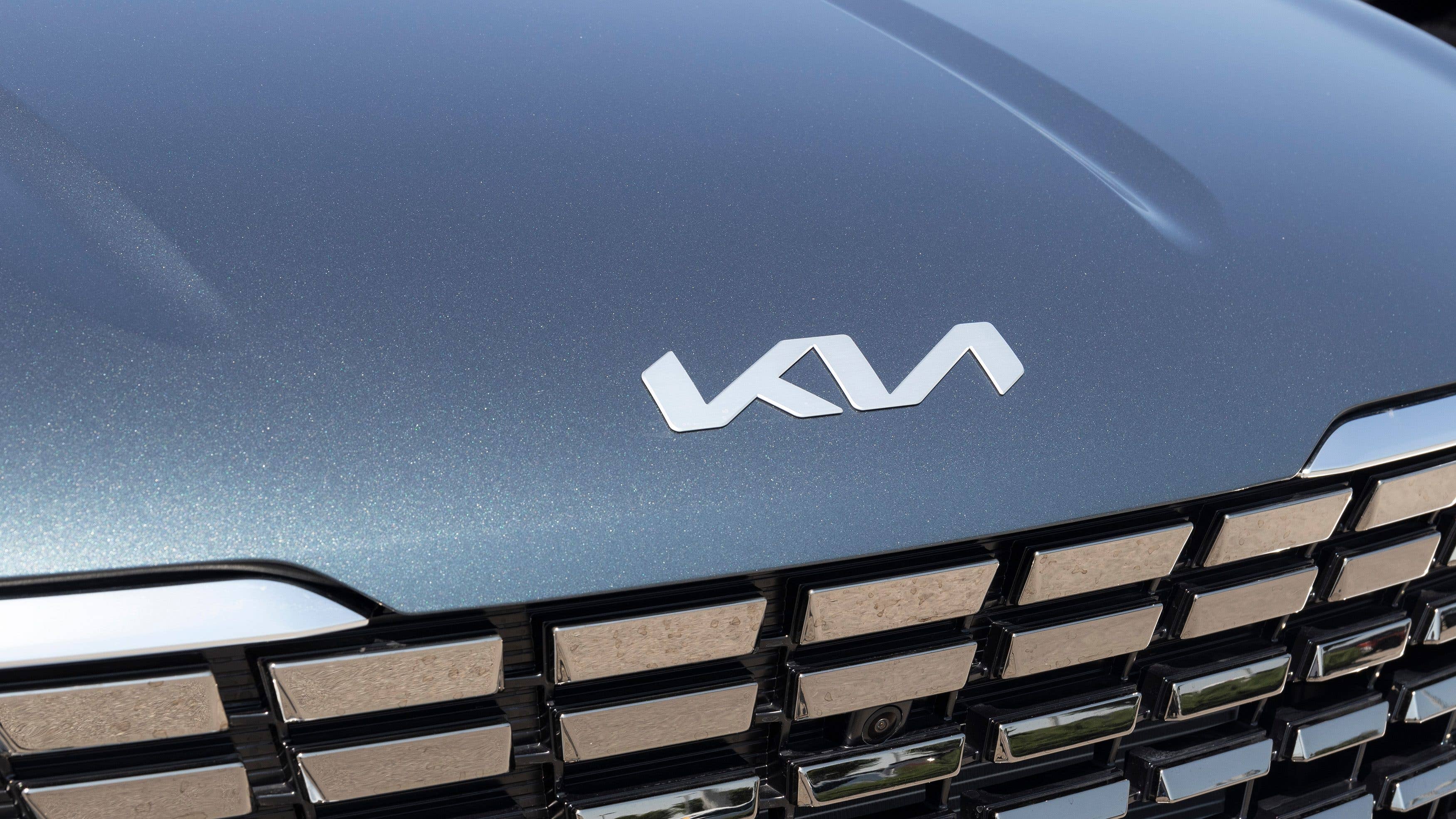 Close-up of a Kia logo on a vehicle's front grille.