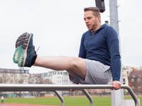 A man performs an exercise on a railing at an outdoor sports field.