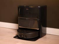 Mova Z60 Ultra Roller Complete, a black robotic cleaner against a dark wall.