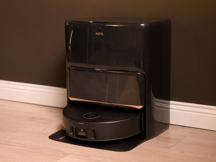 Mova Z60 Ultra Roller Complete, a black robotic cleaner against a dark wall.