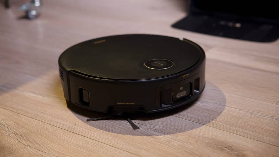 A black robot vacuum cleaner on a wooden floor.