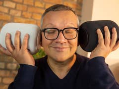 NextPit editor holding two HomePods in each ear