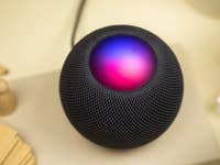 The HomePod mini on the table with colorful lights displaying on the top touch screen