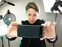 A person taking a picture with the Google Pixel 6a surround by lights