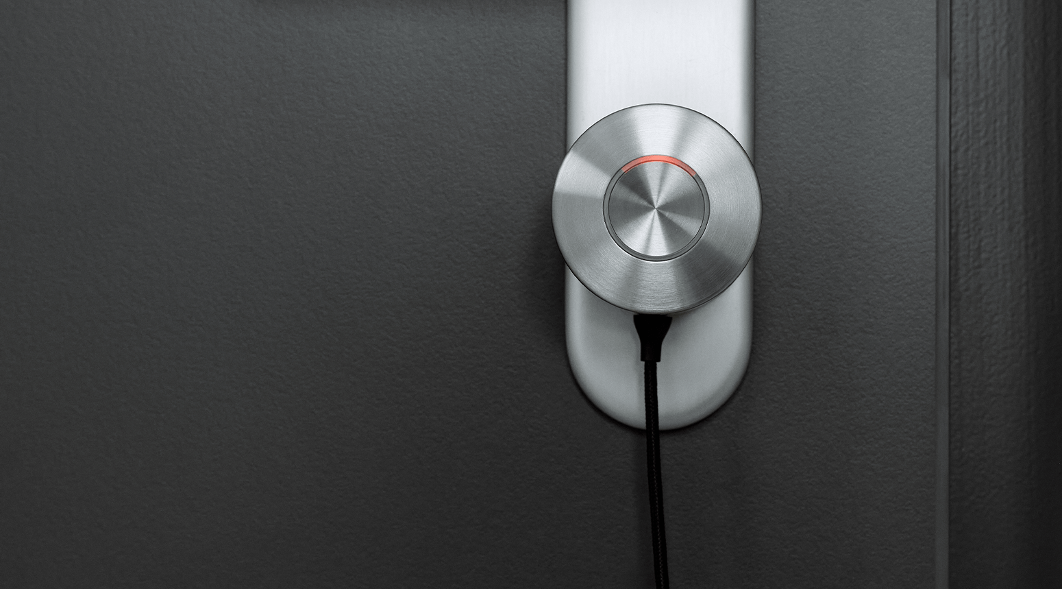 Close-up of a Nuki Smart Lock Ultra mounted on a door with a black cable attached.