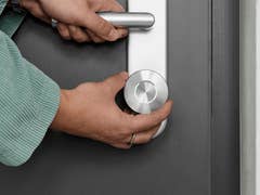 A person is using a Nuki Smart Lock Ultra on a door handle.