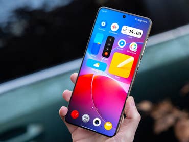 A person holding a OnePlus 13 smartphone displaying a colorful home screen.