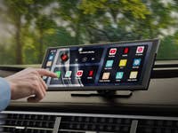 A hand interacting with an Ottocast touchscreen display in a car, showing various app options.