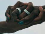 Two hands clasped together, wearing Oura Rings, against a cloudy sky.