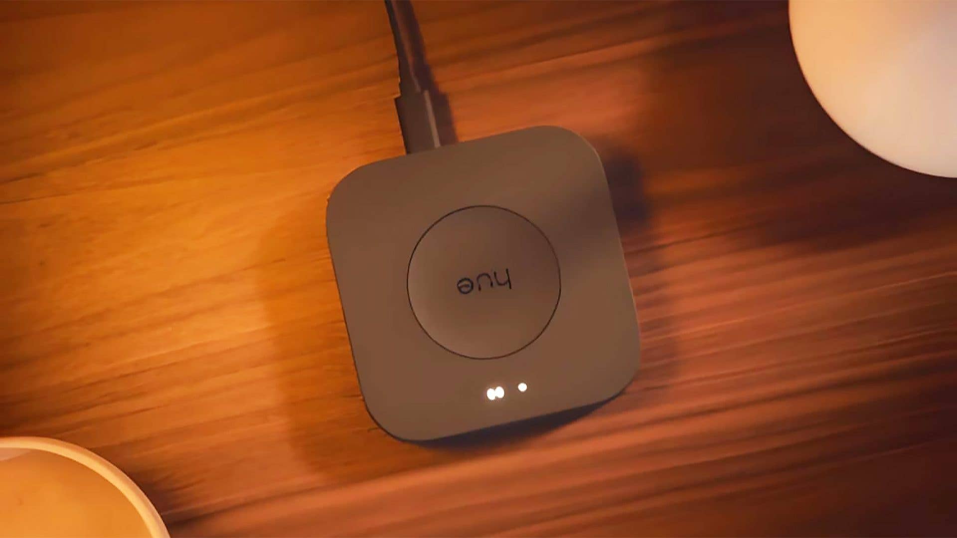A Philips Hue smart lighting hub on a wooden surface.