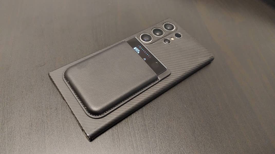 A smartphone with a black leather case placed on a textured surface. A smartphone with a black leather case placed on a textured surface.