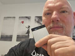 A person holding a small device labeled '97%' in front of artwork featuring a girl with a balloon.