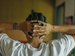 A person with braided hair, wearing a Polar Loop, rests hands behind their head in a relaxed pose.