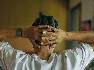 A person with braided hair, wearing a Polar Loop, rests hands behind their head in a relaxed pose.