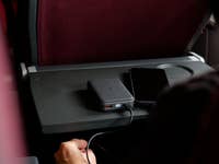 A power bank connected to a smartphone on a tray table in an airplane.