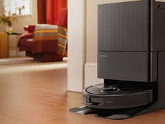 Roborock Qrevo S5V robot vacuum mop with self-wash dock in a modern living room.