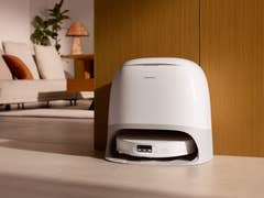 Roborock Qrevo CurvX robot vacuum stored in a sleek white charging dock in a modern living room.